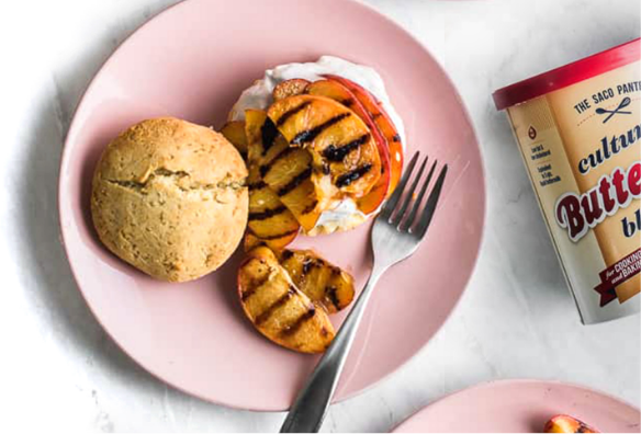 overhead shot of grilled peaches in a buttermilk biscuit and a canister of Saco Pantry Cultured Buttermilk