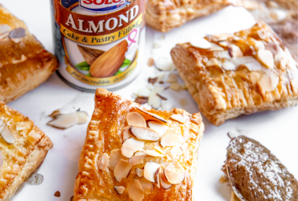 Almonp puff pasties around a can of Solo Foods Almond Cake and Pasty Filling on white parchment paper
